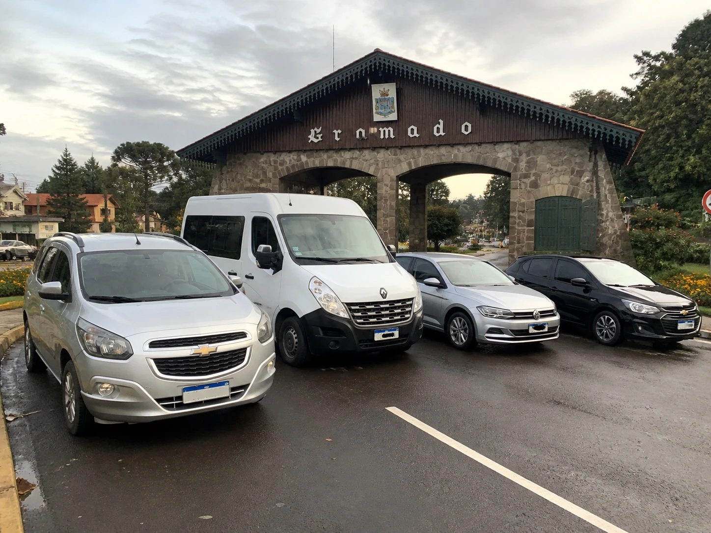 Veículos e van da agência em frente ao pórtico de Gramado